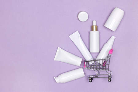 Cosmetic beauty products with shopping cart on purple background. Skin care cosmetics sale concept. copy spaceの写真素材