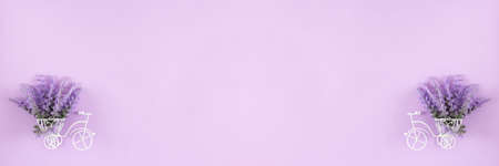 Small white bicycle with lavender bouquet in basket on pastel purple background. spring floral banner backgroundの写真素材