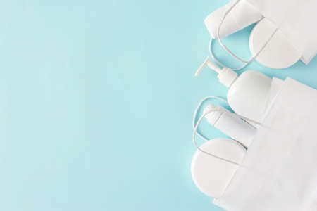 Cosmetic products in white paper merchandise bag on pastel blue background. Buying cosmetics. Beauty shopping and sale concept. flat lay. copy spaceの写真素材