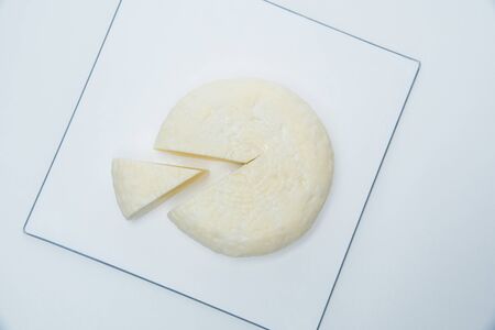 Traditional Russian Adygei cheese served on white cutting plate isolated over white backgroundの写真素材