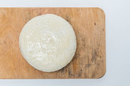 Traditional Russian Adygei cheese served on wooden cutting board isolated over white background