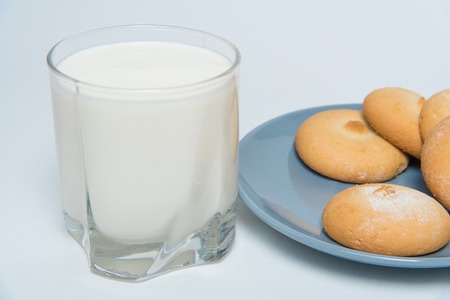 Glass of milk and plate with cookies isoleted over white backgroundの写真素材