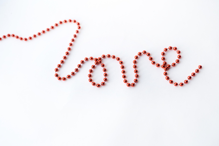 The word LOVE - declaration of written with red beads isolated on white backgroundの写真素材
