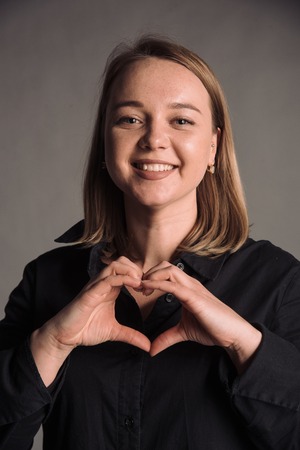 portrait of smiling young woman with in black shirt isolated on gray studio background