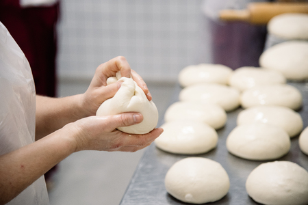 Female hands preparing dough for pizza closeup, restaurantの写真素材