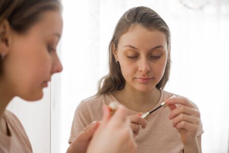 Portrait of attractive young woman putting on makeupの写真素材