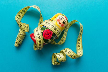 nesting doll matrioshka with tailor's meter on blue background. minimal concept. top view.の写真素材