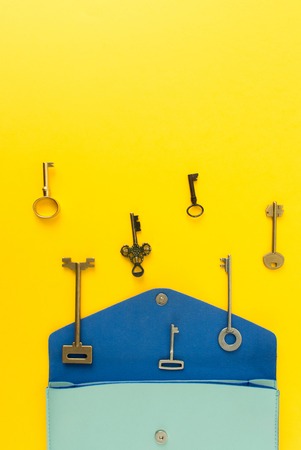 Flat lay of cute woman bag open out with a lot of old keys on colorful background with copy space.の写真素材