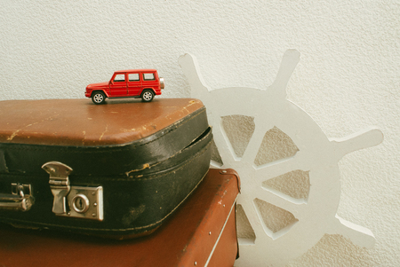 Part of leather travel valises or old suitcase with red toy car and vintage white steering wheel .の写真素材