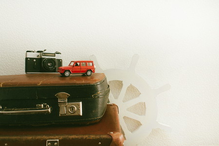 Part of leather travel valises or old suitcase with red toy car and vintage white steering wheel .の写真素材