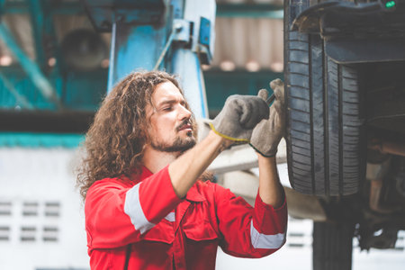 Auto mechanic working in garage, Technician man working in auto service with lifted vehicle, Car repair and maintenanceの写真素材