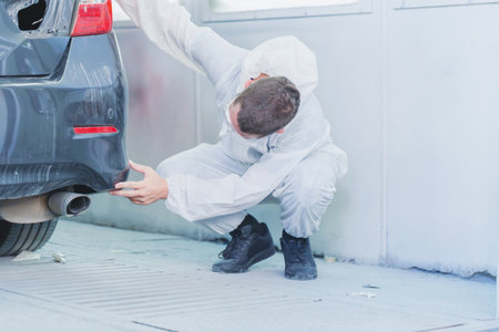 The mechanic man painting car in chamber, Technician checking the quality of the painting, Garage painting car service repair and maintenanceの写真素材