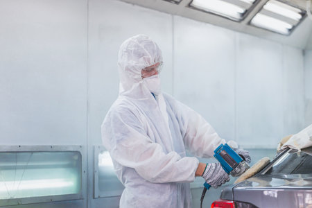 Mechanic man works with grinding tool. Sanding of car elements. Garage painting car repair serviceの写真素材