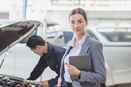 Manager and auto mechanic in auto repair shop, Mechanic and young woman client talking together at the repair garage, Car repair and maintenanceの写真素材
