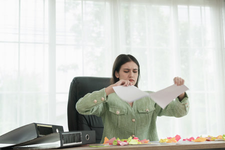 Woman angry paper office, Young stressed woman sitting at desk in office ripping documents with...
