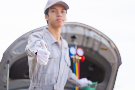 Technician showing thumbs up checks car air conditioning system refrigerant recharge, Repairman with...