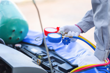 Repairman holds monitor tool to check and fix car air conditioner system, Technician checks car air conditioning system refrigerant recharge, Car Air Conditioning Repairの写真素材