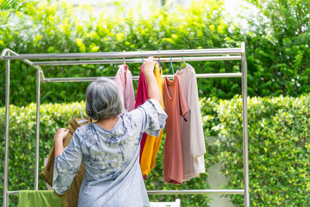 Senior woman hanging laundry outside, Asian senior woman drying clothes in backyardの写真素材