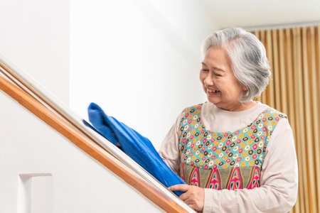 Cheerful senior woman housekeeping, Happy woman cleaning the house, Professional female housekeeper with cleaning toolsの写真素材