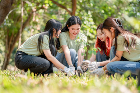 Cheerful Young Volunteers Planting Tree for Environmental Conservation, Eco-Friendly Group Activity: Teamwork in Tree Plantingの写真素材