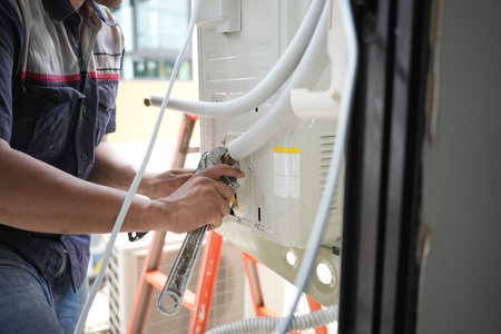 Close-Up of HVAC Maintenance and Repair Work, Professional Air Conditioner Installation or Service in Progress, Technician Repairing Outdoor Air Conditioning Unit with Wrenchの写真素材