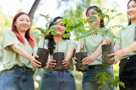 Group of Young People Holding Tree Saplings for Planting, Asian Volunteers Participating in a Reforestation Project, Community Effort for Environmental Conservation and Green Futureの写真素材