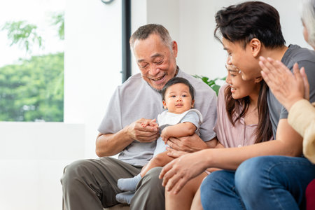 Portrait of Happy Asian Family at Home, Happy Grandparents, Parents, and Baby Bonding on Sofa,...
