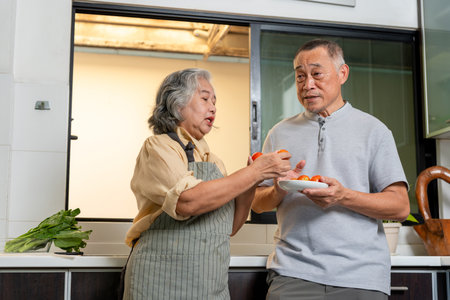 Joyful Grandparents Enjoying Culinary Hobby at Home, Happy Senior Asian Couple Cooking Healthy Meal Together, Elderly Man and Woman Preparing Fresh Ingredients in Kitchenの写真素材