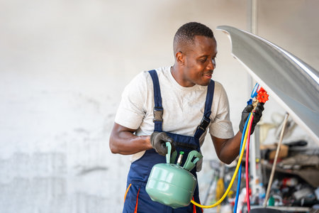 Technician Man Checking Car Air Conditioning System Refrigerant Recharge, Mechanic with AC Refrigerant Manifold Gauge Set Repair Car Air Conditioning in Workshopの写真素材