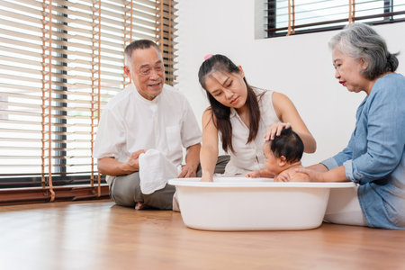 Multi-Generational Asian Family Bathing Baby Together, Grandparents and Mother Care for Infant in Home, Joyful Family Moment, Baby's Bath Timeの写真素材