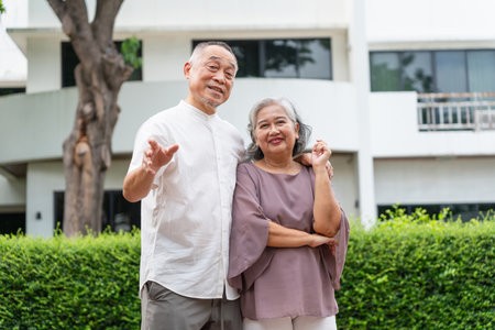 Happy Senior Asian Couple Standing Together Outdoors, Portrait of a Smiling Elderly Asian Pair in Front of Homeの写真素材