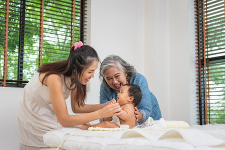 Happy multigenerational Asian family bonding time with baby at home, Grandmother, mother, and baby...
