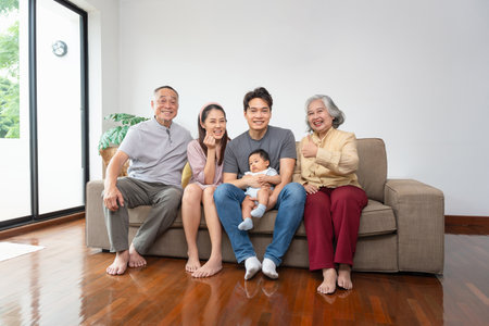 Joyful Grandparents, Parents, and Baby Posing Together on Couch, Happy Asian Multi-Generational...