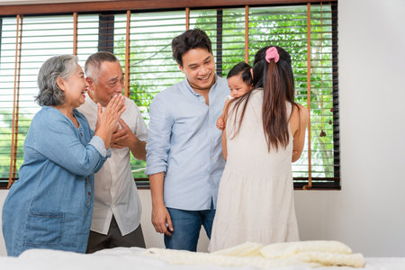 Portrait of Happy Asian Family at Home, Happy Grandparents, Parents, and Baby Bonding in Bedroom, Multi-Generational Asian Family Smiling Together at Homeの写真素材