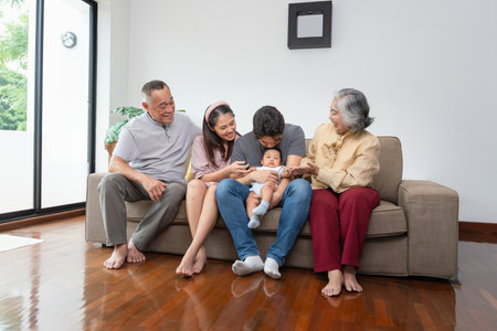 Portrait of Happy Asian Family at Home, Happy Grandparents, Parents, and Baby Bonding on Sofa,...