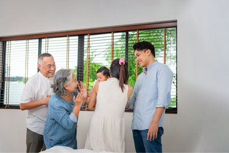 Portrait of Happy Asian Family at Home, Happy Grandparents, Parents, and Baby Bonding in Bedroom, Multi-Generational Family Smiling Together at Homeの写真素材