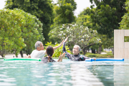 Senior Couple High-Fiving in Pool During Water Aerobics or Hydrotherapy, Aqua Fitness Class,...