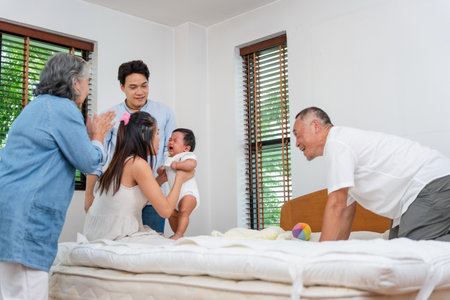 Asian multigenerational family comforting crying baby at home, Parents and grandparents supporting...