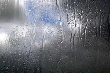 Rain drops on glass with dark clouds. Weather forecast.の写真素材