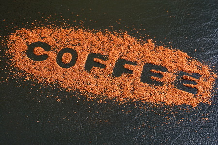 The word coffee written on a scattered powdered coffee on a black background.の写真素材