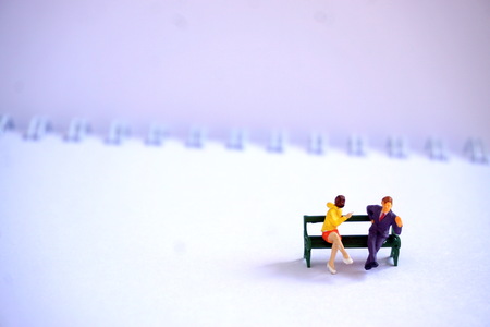Miniature figures of businessmen sitting on a bench. Notebook in the background. The concept of discussing the problem.の写真素材