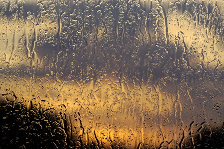 Raindrops on the glass at sunset. Rainy weather forecast.の写真素材
