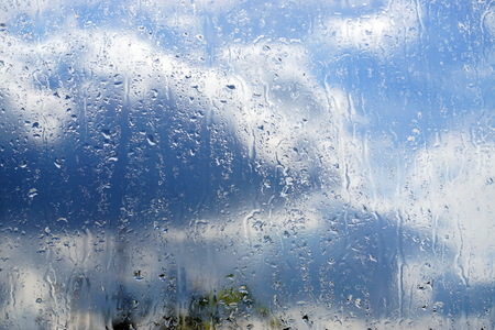 Raindrops on the glass, water drips, dark autumn clouds. The concept of the bad weather forecast.の写真素材