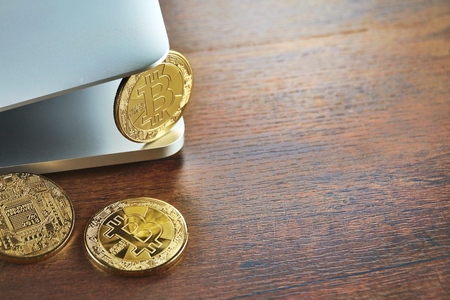 Golden Bitcoins (Cryptocurrency) on laptop.Top view stack of Digital coins on computer keyboard and wooden desk table background.Flat lay blank text.Copy space for word.の写真素材