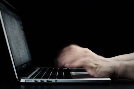 Close up of man hands typing on laptop computer in blurred motion with copy space above selective focus on black background.Working hard in home office.Business concept.workplace with blank for text.の写真素材