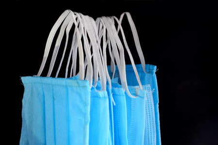 Hanging blue surgical mask separated in black backdropの写真素材