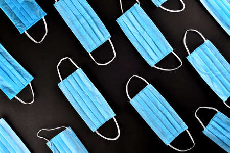 A flat lay photo of blue surgical mask in black backdropの写真素材