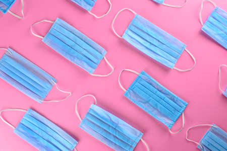 A flat lay photo of blue surgical mask in pink backdropの写真素材