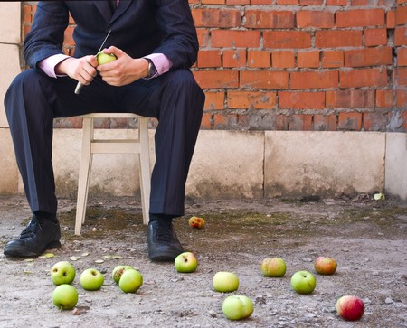 the businessman cleaning apples sitting on a stoolの写真素材