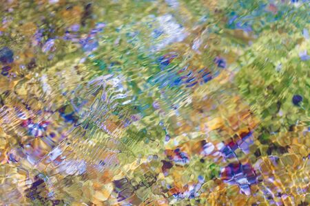 Waving water at shallow of sea beach with colored seabedの写真素材